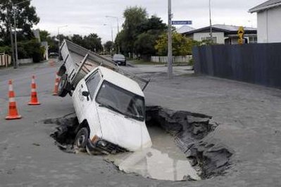 Ô tô bị mắc kẹt giữa một con phố bị sụt lún bởi động đất tại Christchurch.
